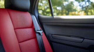 Interior view of a car seat with red upholstery and seatbelt.